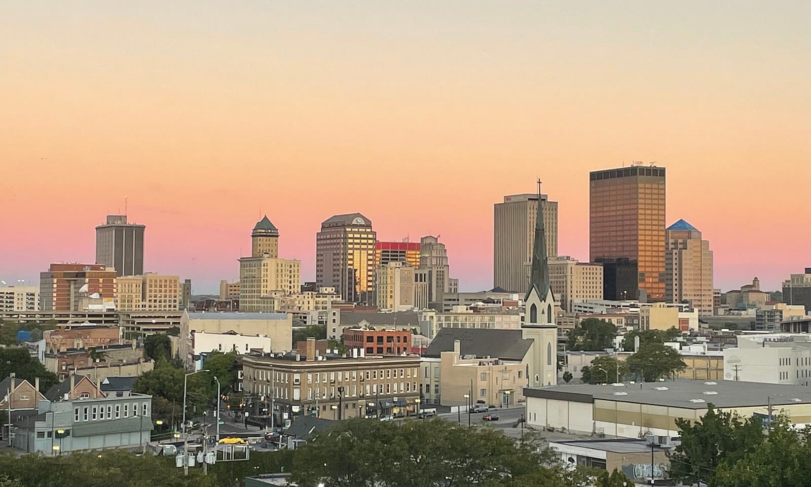 The downtown Dayton skyline under a pink and orange sunset sky: Rockstarr Media is casting new faces in Dayton