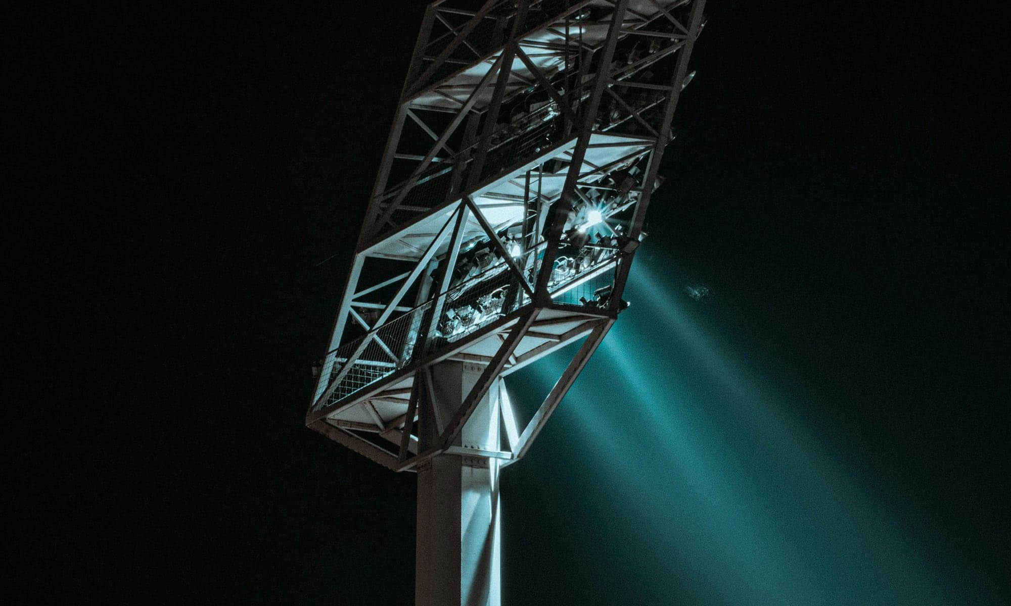 Stadium floodlights shining over a field at night